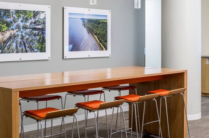 An MPCA touchdown workstation with nature photography and orange chairs.