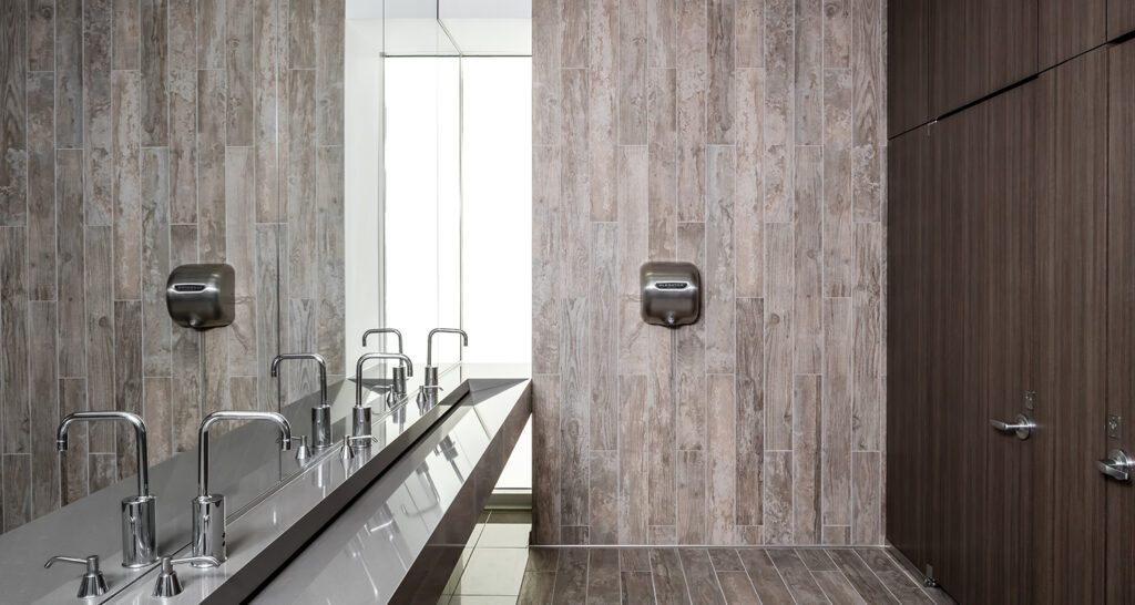 Inclusive restroom design in the Anytime Fitness corporate headquarters facility, including bright lighting and floor to ceiling enclosed restrooms.