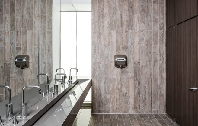 Inclusive restroom design in the Anytime Fitness corporate headquarters facility, including bright lighting and floor to ceiling enclosed restrooms.