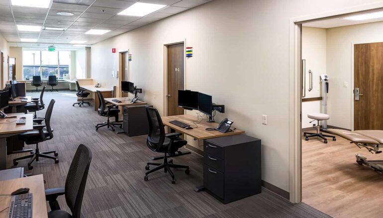 View of an interior staff core, with open workstations and double-loaded exam room access.
