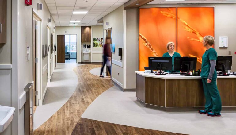 Nurse station and corridor in the pre/post-orthopedic suite, featuring wood accents and floor to ceiling wall graphics.