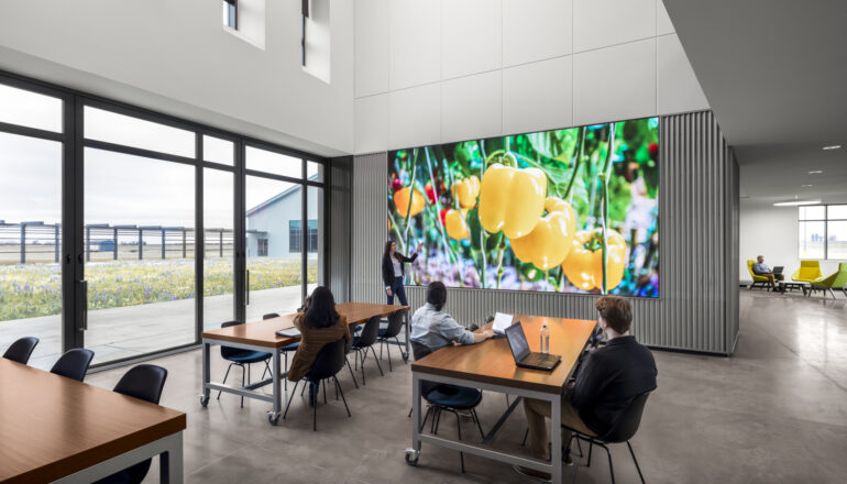 People utilize a large monitor for a presentation in a work cafe.