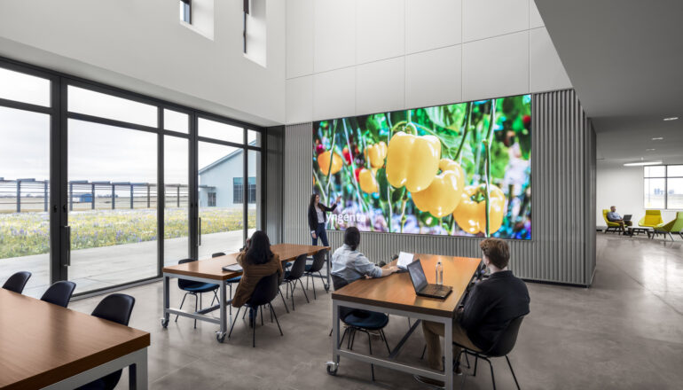 People utilize a large monitor for a presentation in a work cafe.