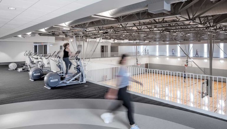 A jogger on the walking track passes an overlook into one of the gymnasiums.