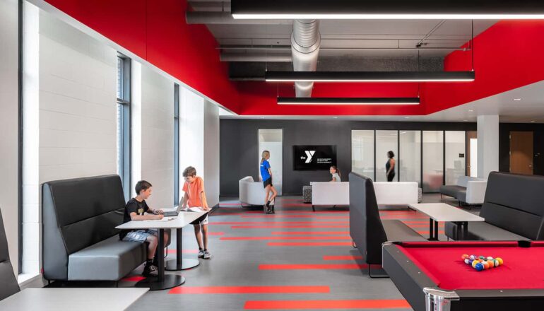 Teen recreation room with a variety of seating, red accents, and a pool table.