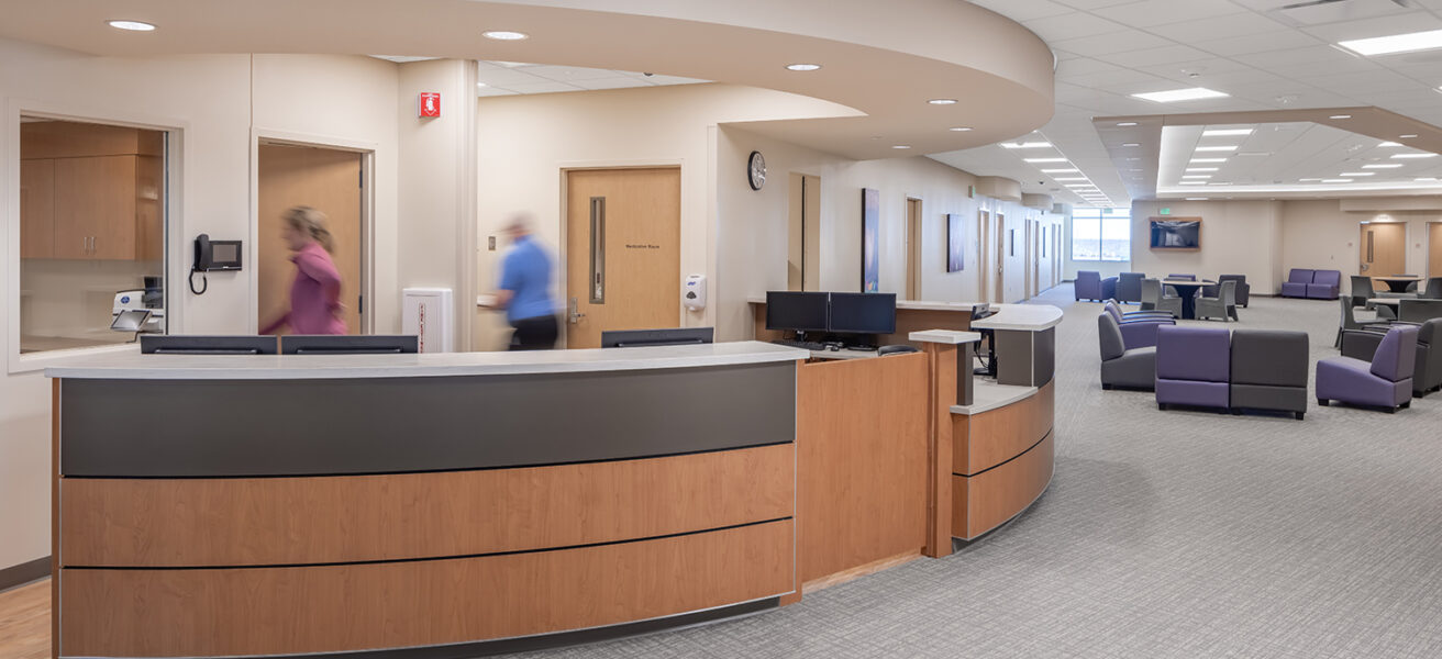 Two people walk behind a nurse station in the Avera Behavioral Health Center addition