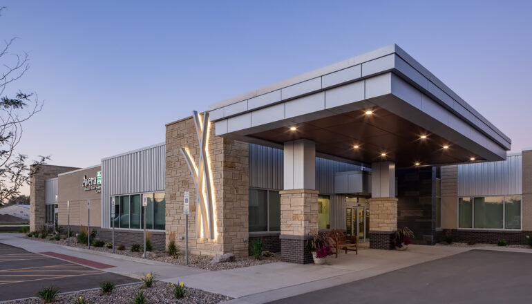 Exterior view of an Avera Missouri River entry at dusk with lighted prairie grass designs.