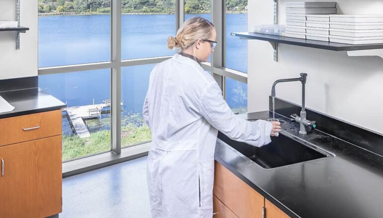 A student utilizing a lab space with an expansive view to a lake near campus.