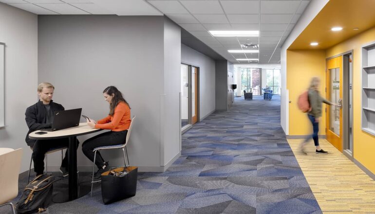 A typical corridor with touchdown space for students to gather and lab entry emphasized by bright colors and built-in storage.