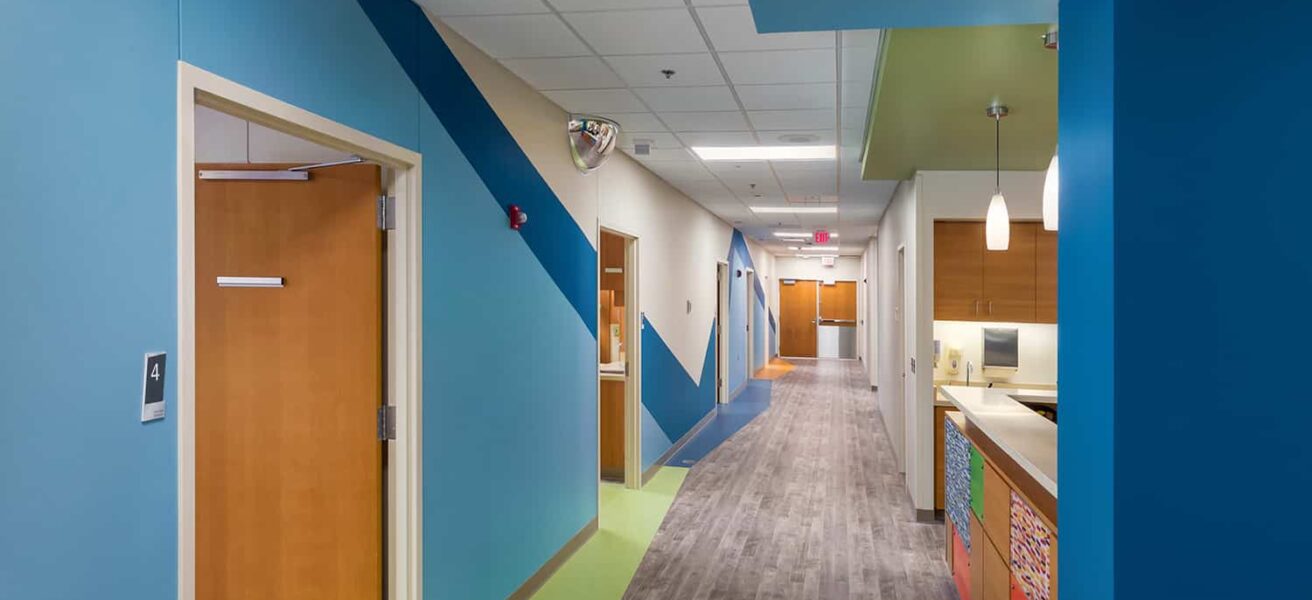 Pediatric unit corridor with a blue wall theme and view to the nurses station.