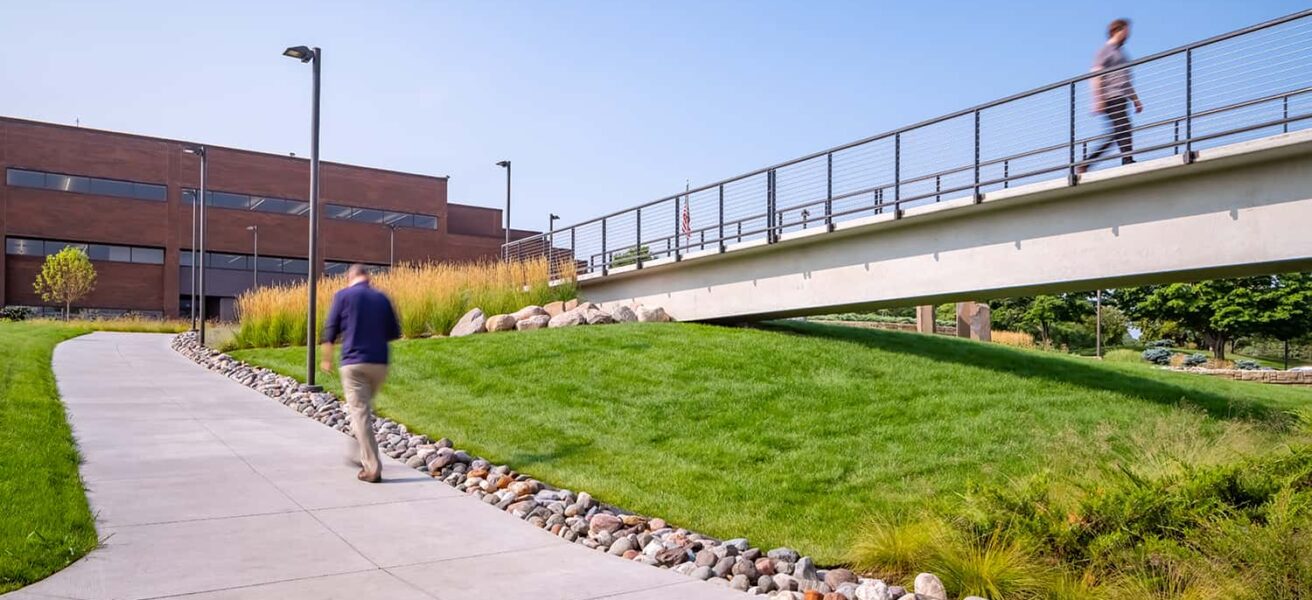 People walking to and from the CHS parking ramp to the office, using the sidewalks and pedestrian bridge.