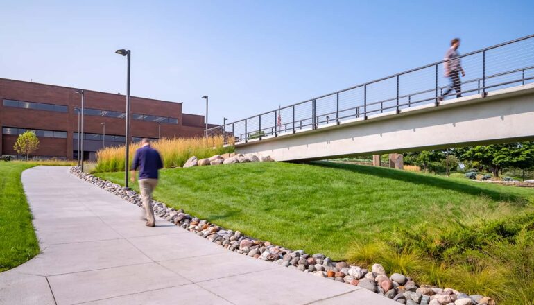 People walking to and from the CHS parking ramp to the office, using the sidewalks and pedestrian bridge.