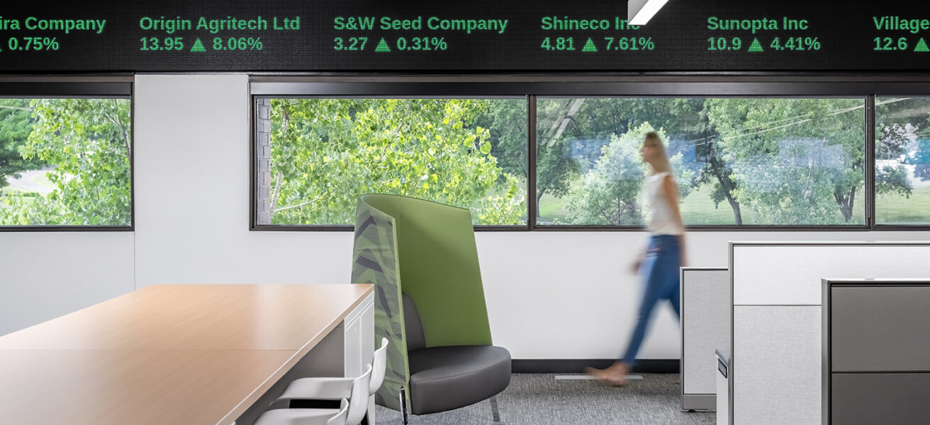 Office workspace with views to nature and trading floor digital panels at ceiling level.