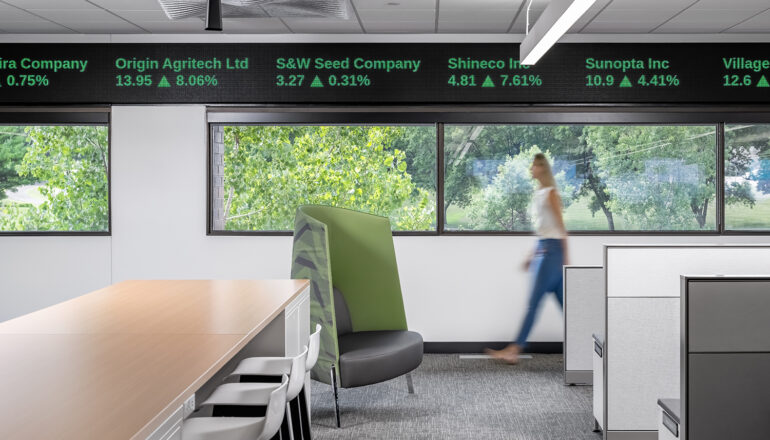 Office workspace with views to nature and trading floor digital panels at ceiling level.