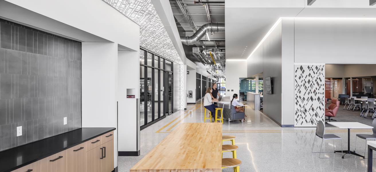 A long view into the CVTC TEC, with student coffee station, touchdown study areas, and windows into education bays.