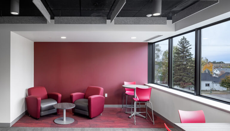 Red armchairs, task chairs, and feature wall all create a cohesive study nook in a student lounge