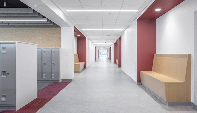 A red themed corridor is home to locker bays and drop-in benches outside of classrooms at Cotter Schools