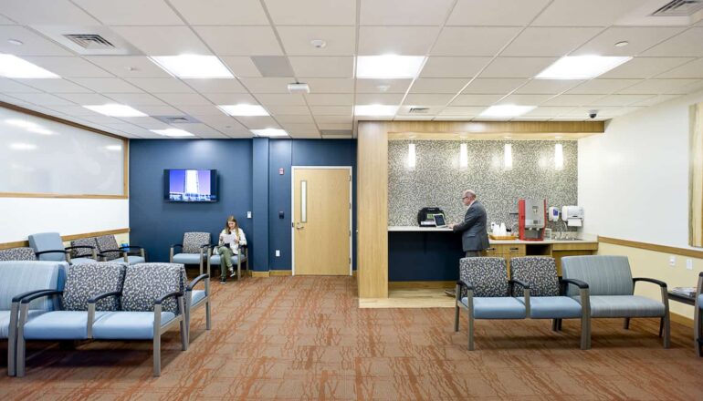 A patient waiting area has a coffee station and options for seating to accommodate various size groups of visitors