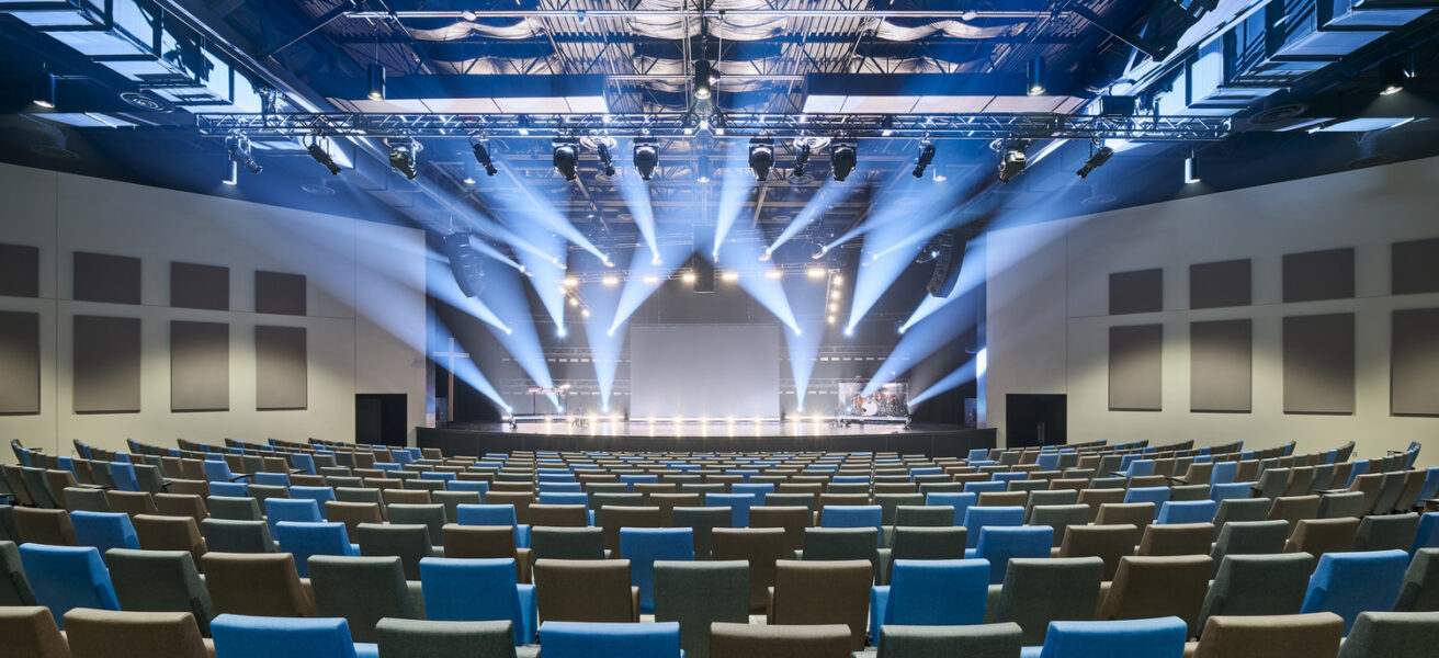 Blue-toned spotlights illuminate the Eagle Brook Apple Valley church auditorium's stage.