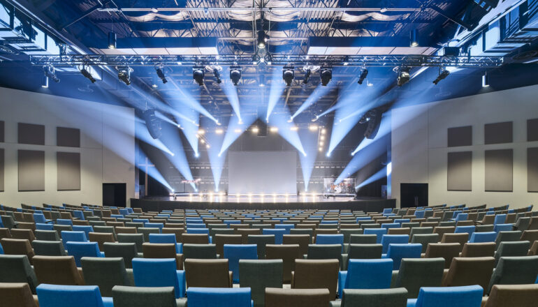 Blue-toned spotlights illuminate the Eagle Brook Apple Valley church auditorium's stage.