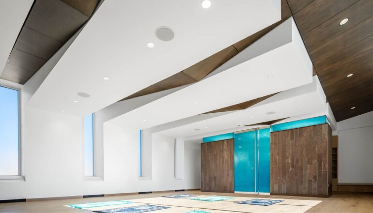 Full view of the multifaith center with worship mats on the floor and illuminated blue privacy glass at the entry.