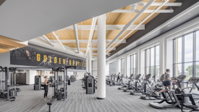 The main cardio area in the Lund Center features expansive views, high wood paneled ceilings, and branded wall graphics