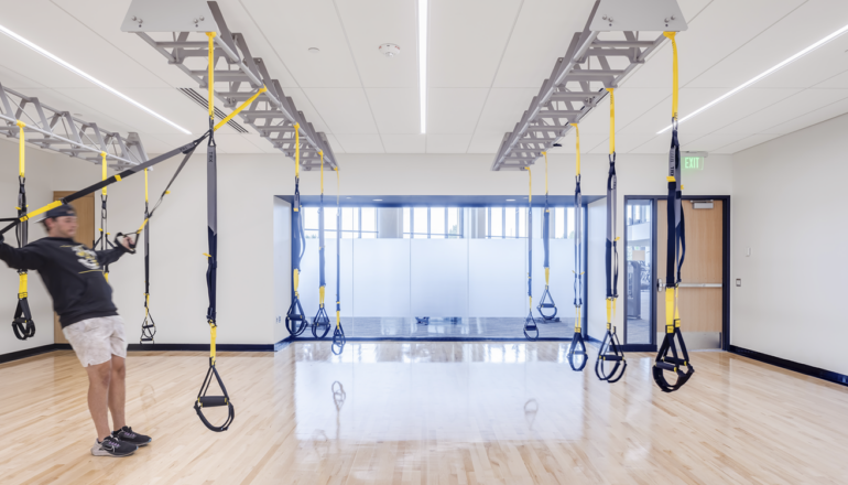 A person uses the suspension training system in a Lund Center fitness studio. An opaque window lights up the studio while maintaining privacy