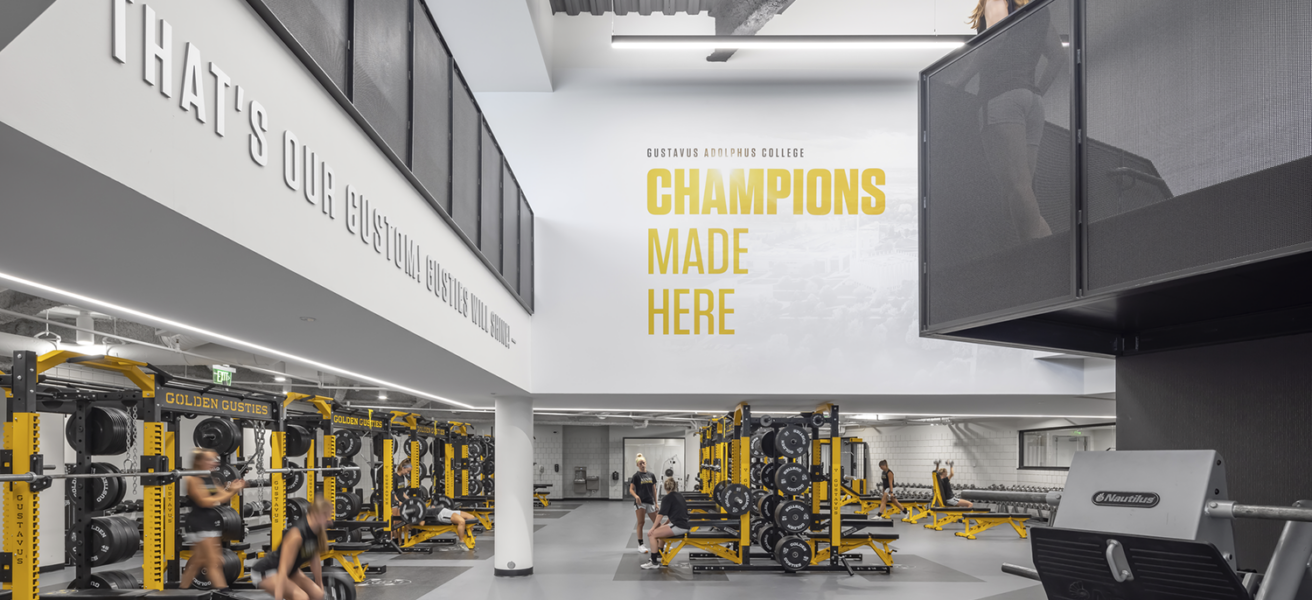 Students work out in the GAC Lund Center weight room, complete with high ceilings and yellow equipment