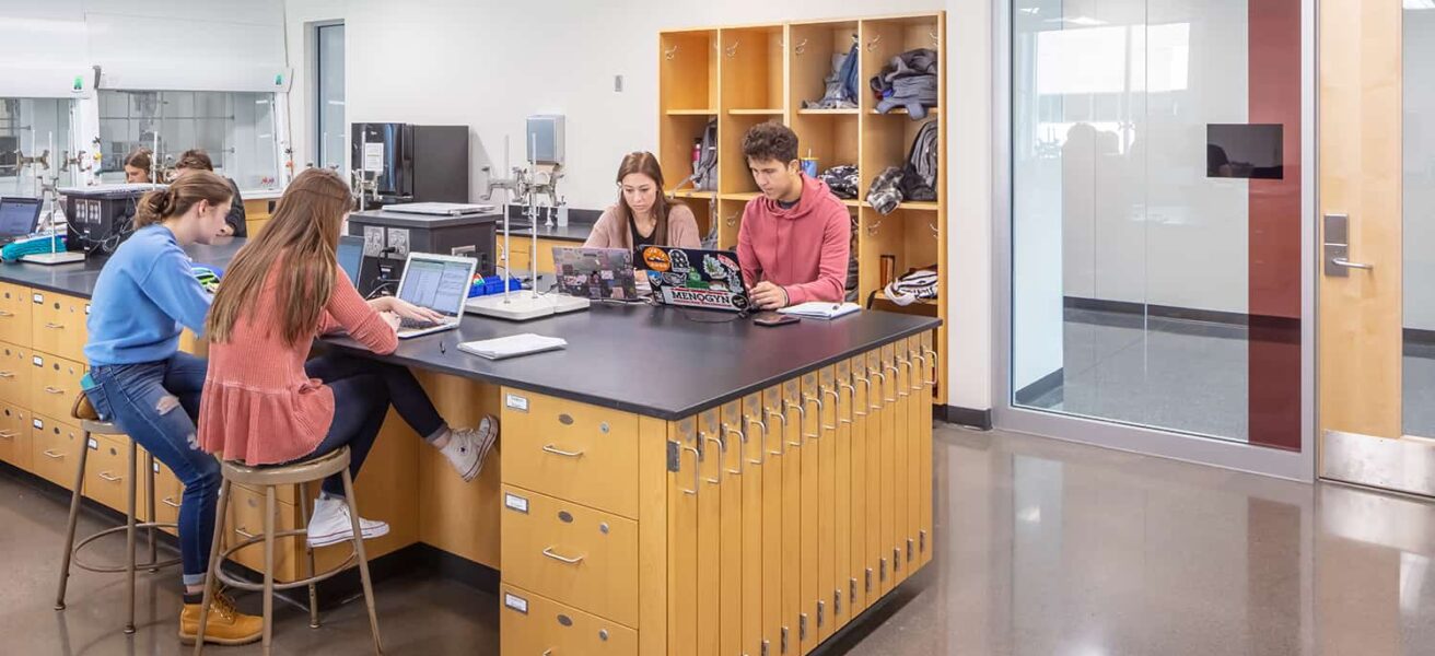 Students working in a lab with transparent views to corridor and storage cubbies.