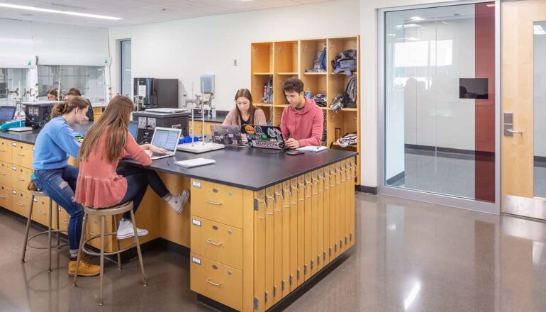 Students working in a lab with transparent views to corridor and storage cubbies.