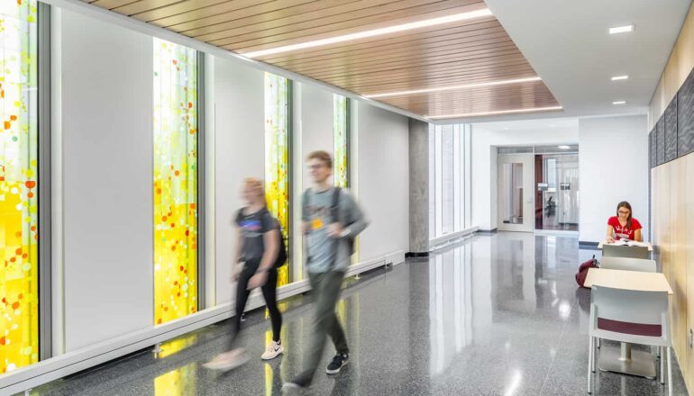Students walking in the skyway entry with window film that represents scientific graphics.