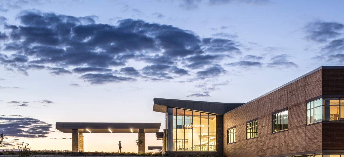 A person walks into the front entry of the JCRHC at dusk, as seen from a distance.