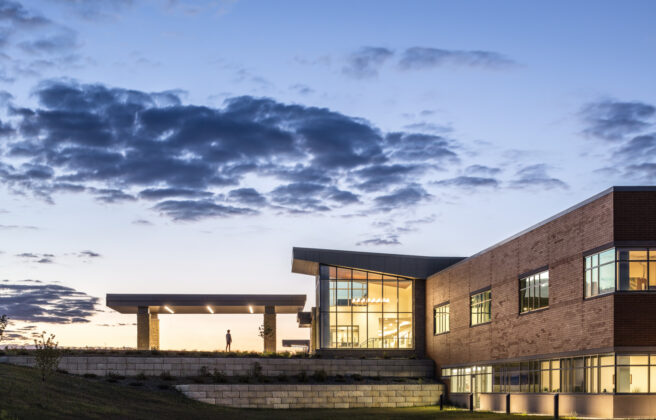 A person walks into the front entry of the JCRHC at dusk, as seen from a distance.