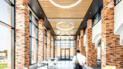 Interior corridor in the entry to the Healthcare Center of Learning, surrounded by exposed brick, wood paneling, feature circular lighting, and open seating.