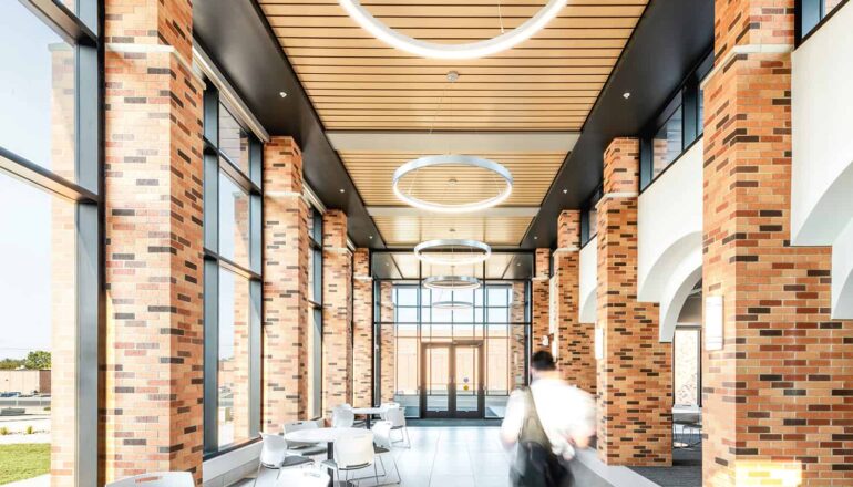 Interior corridor in the entry to the Healthcare Center of Learning, surrounded by exposed brick, wood paneling, feature circular lighting, and open seating.