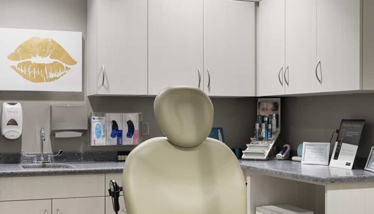 A dermatology procedure room patient chair and staff workstation.