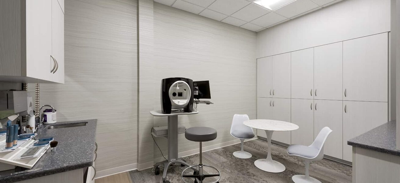 A dermatology procedure room with casework storage and in-room casual seating.