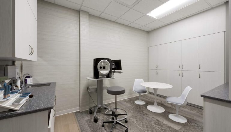 A dermatology procedure room with casework storage and in-room casual seating.
