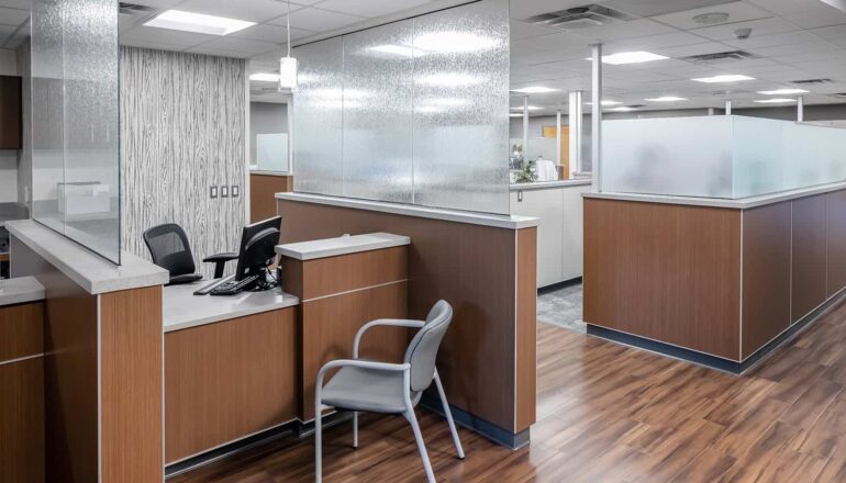 A check-in desk at a nurse station with privacy shields and warm wood tones.