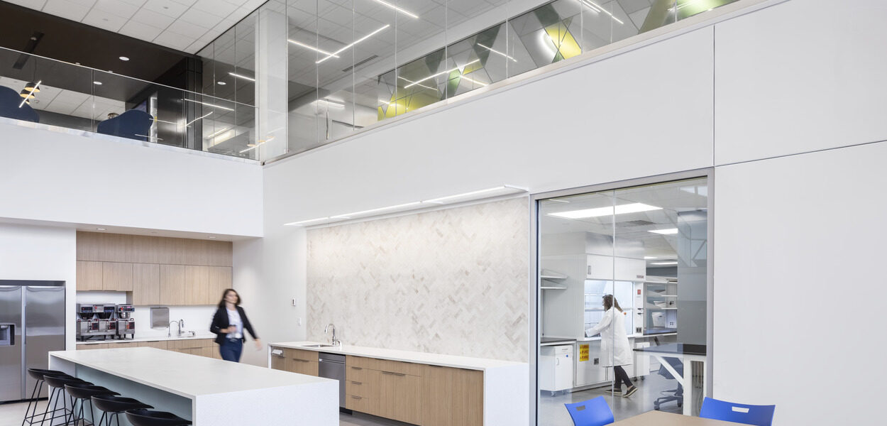 A person walks toward a window looking into the quality control lab.