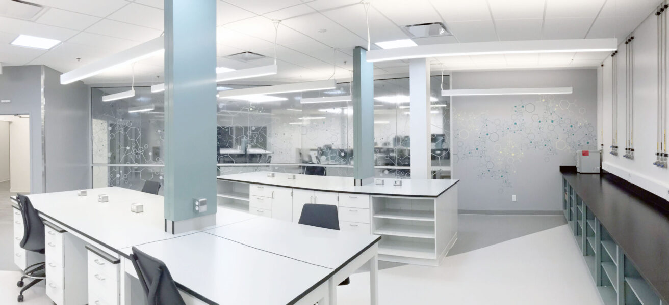 Overall view of workstations in a quality control lab with glass views into adjacent spaces.