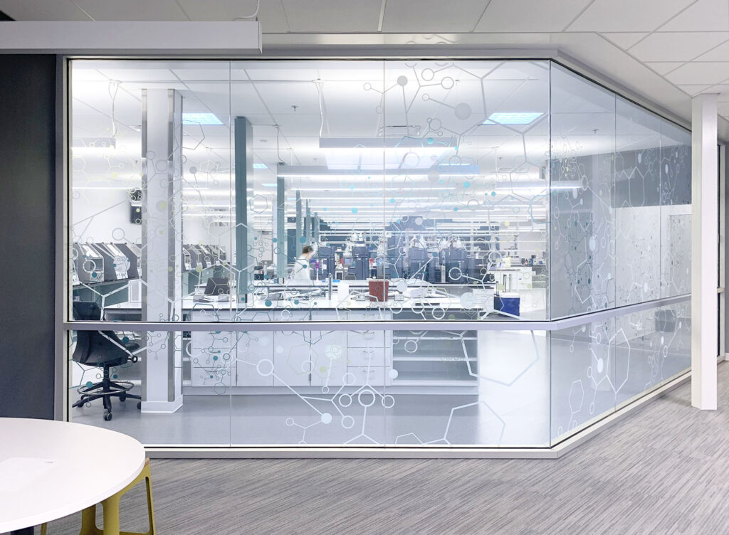 A corridor view into a quality control lab with a graphic design glass pattern.