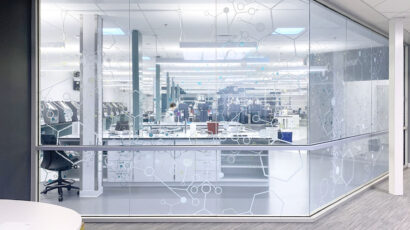 A corridor view into a quality control lab with a graphic design glass pattern.