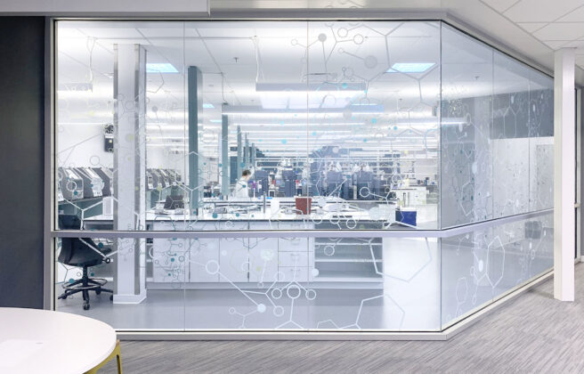 A corridor view into a quality control lab with a graphic design glass pattern.