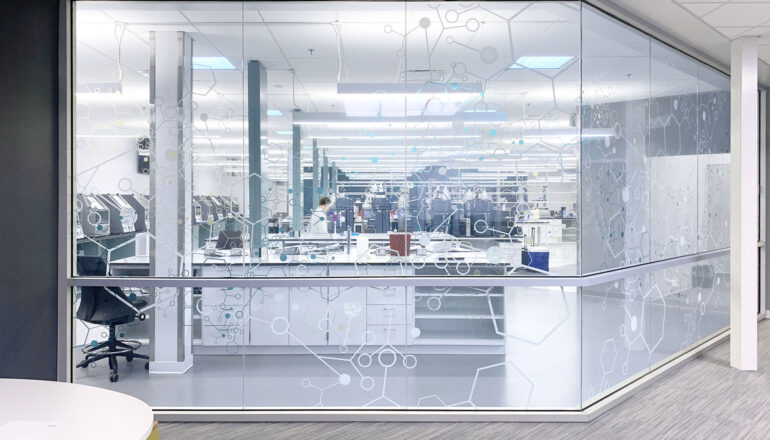 A corridor view into a quality control lab with a graphic design glass pattern.