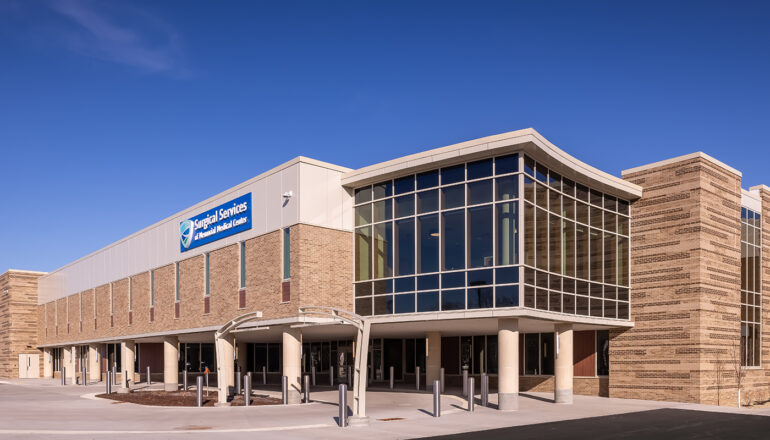 An overall exterior view of the MMC Ashland Surgery Center. The glass-enclosed waiting room sits above the main patient drop-off and entry