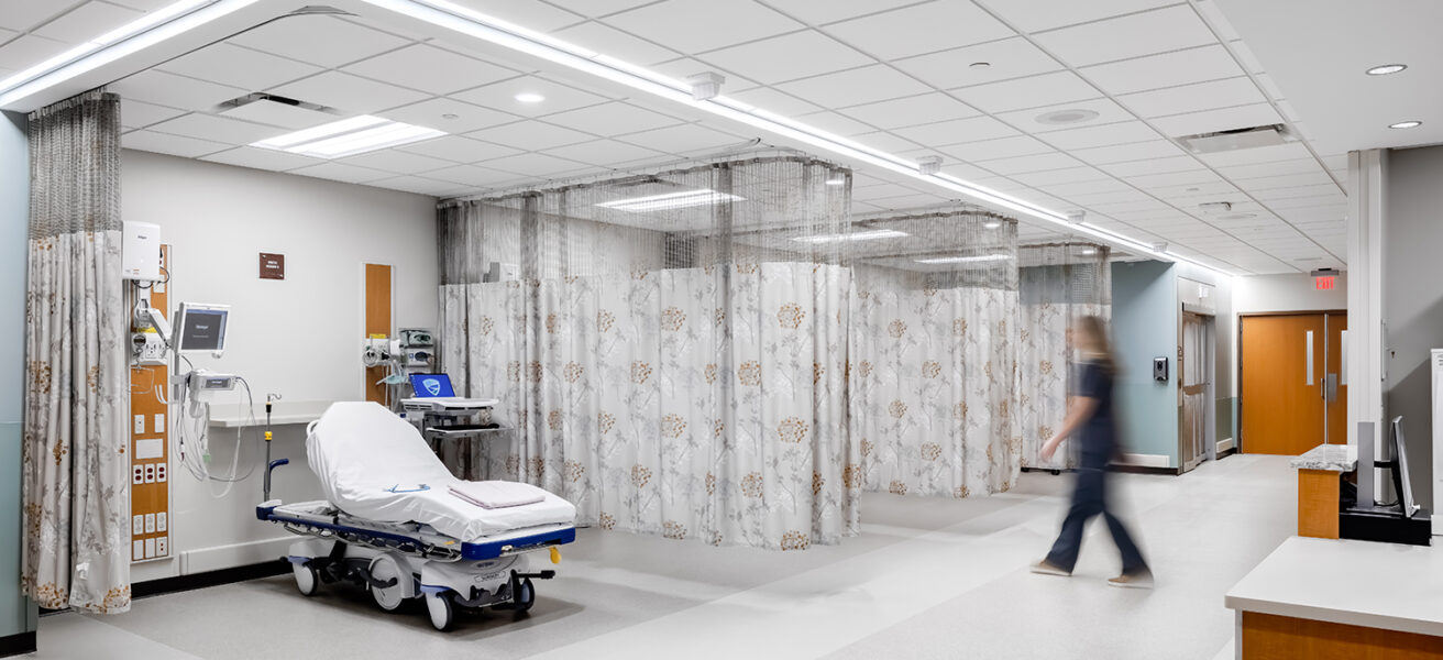 A nurse walks through the MMC Ashland Surgery Center PACU. Patients beds are divided by privacy curtains and are close to staff spaces