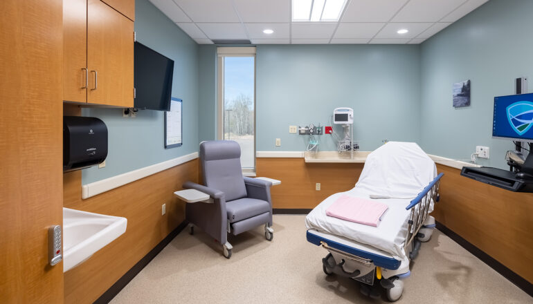 One of the pre-post rooms in the MMC Ashland Surgery Center. The walls are painted a bright blue and wood tone cabinets complete the room