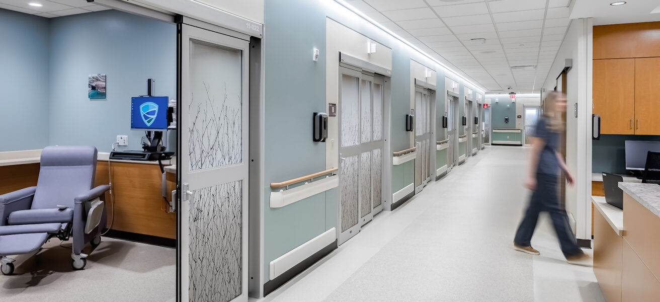 A nurse walks between the pre-post rooms and the nurses station in the MMC Ashland Surgery Center