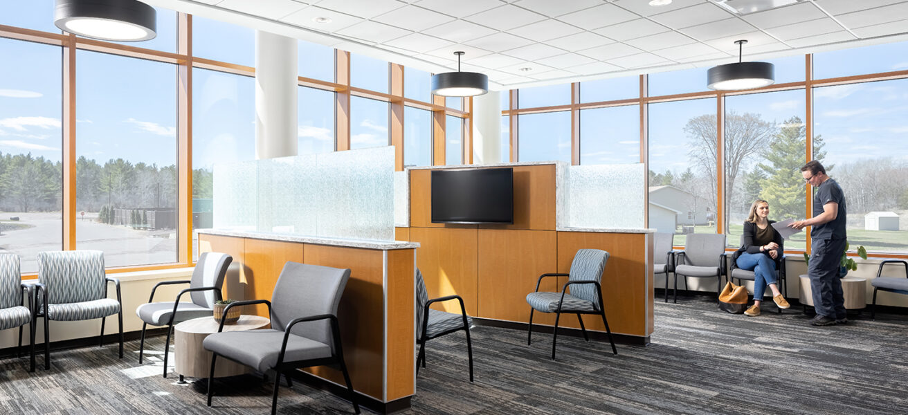 People talk in the waiting room outside of the MMC Ashland Surgery Center. Low privacy dividers and wrap-around floor to ceiling windows keep patients and visitors comfortable